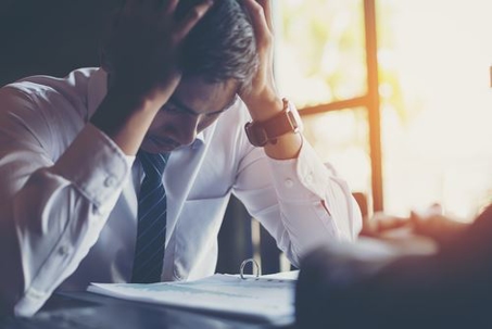 A man with his head in his hands looking at documents
